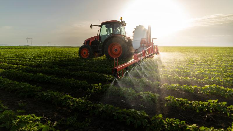 Tractor spraying pesticides on crops. 